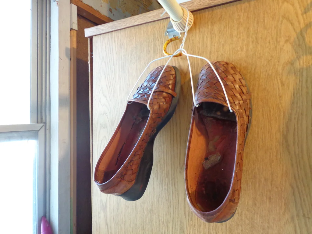 A pair of shoes hanging off some hooks made out of a wire hanger.