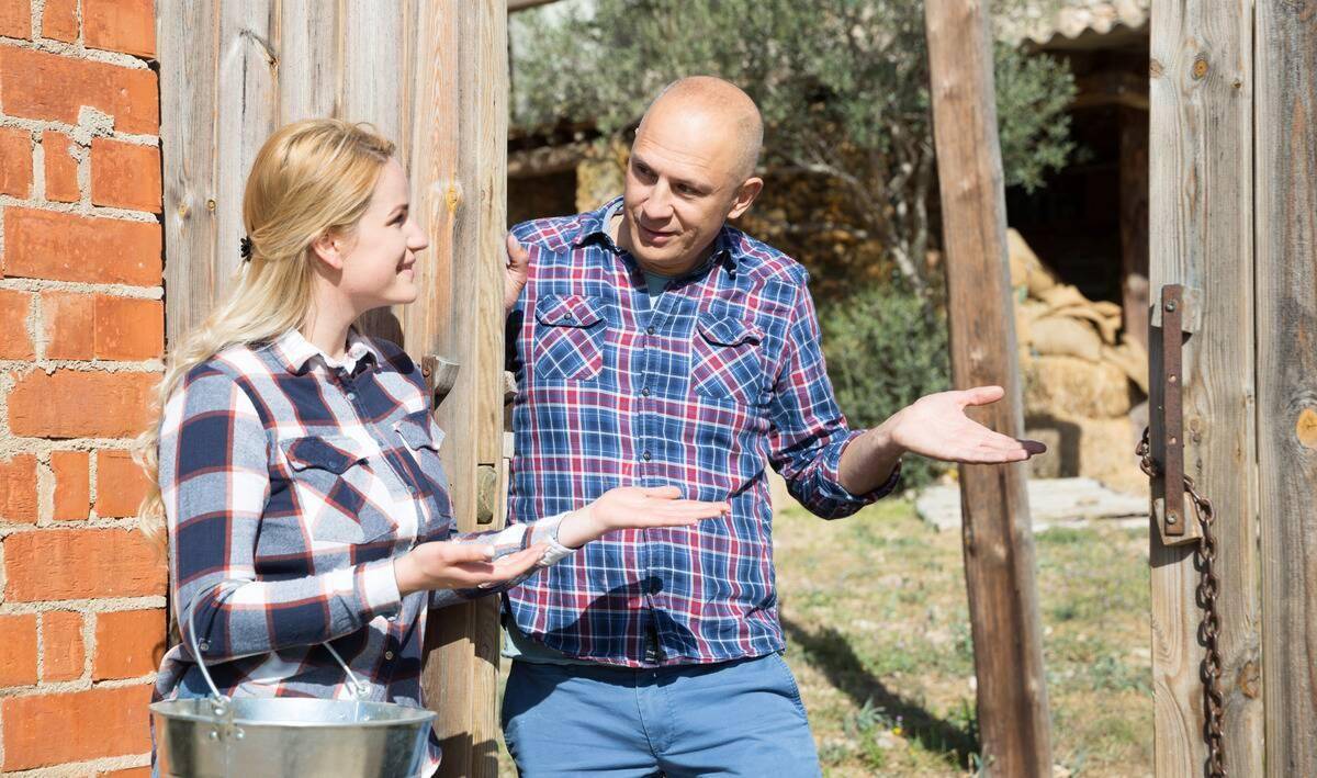 Two neighbors talking in the doorway of a gate.