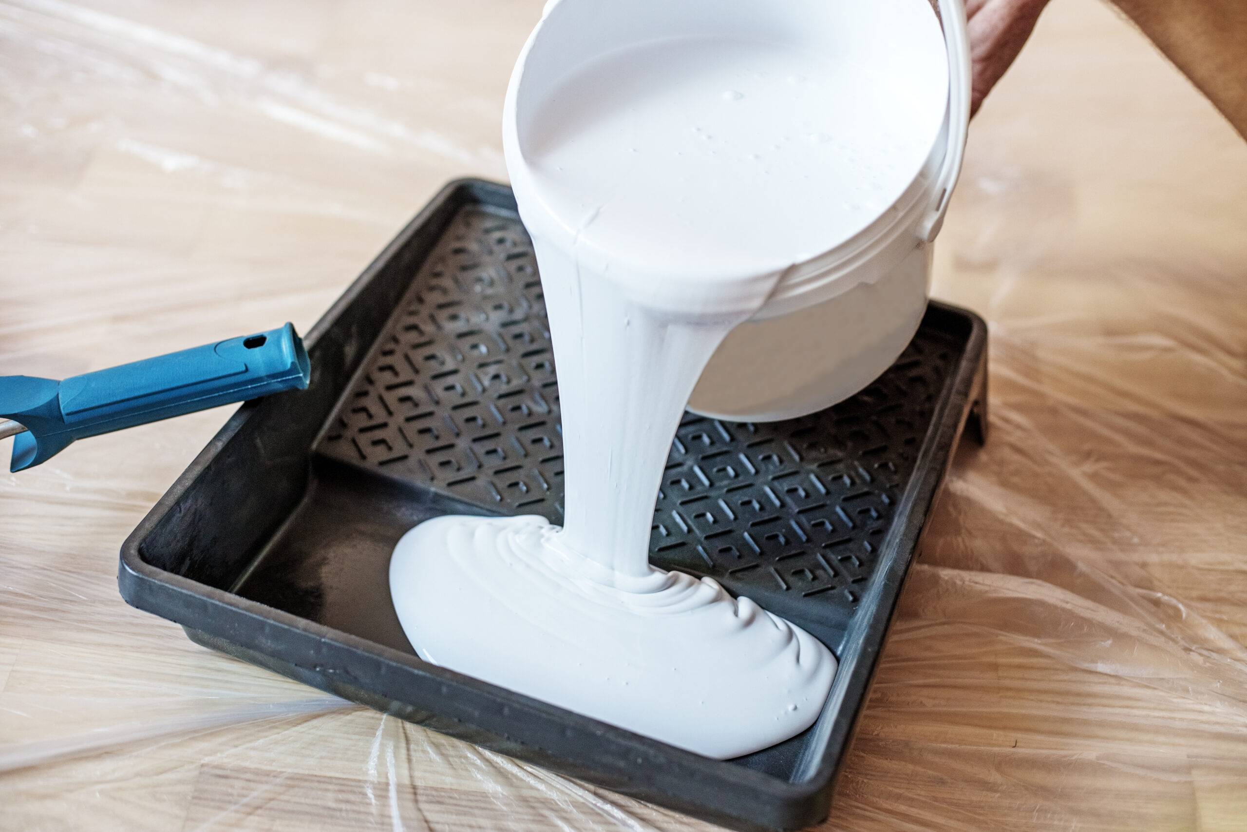 Close up of paint roller in tray. Closeup view of paint tray filled with white paint. Tools for the painter and redecoration