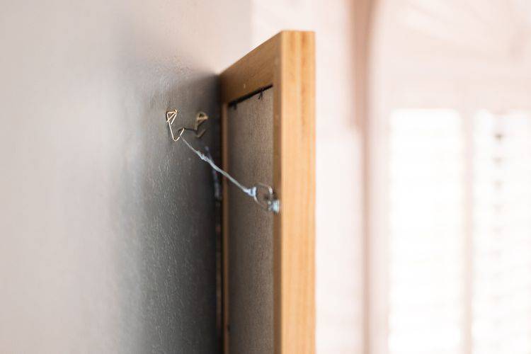 A photo frame on a wall, the hanger made out of a wire hanger.
