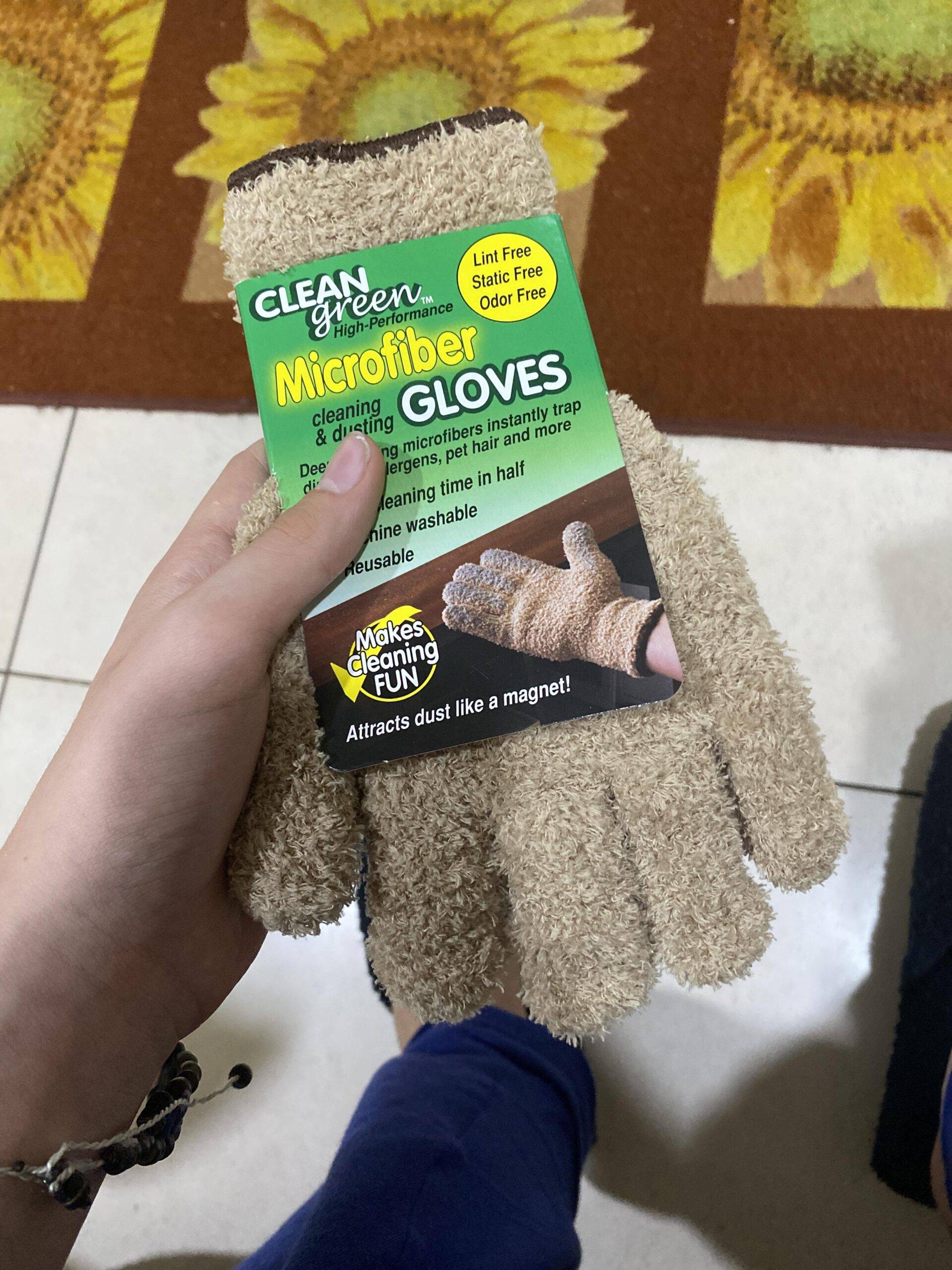 A hand holding a pair of microfiber gloves, still in the packagine.