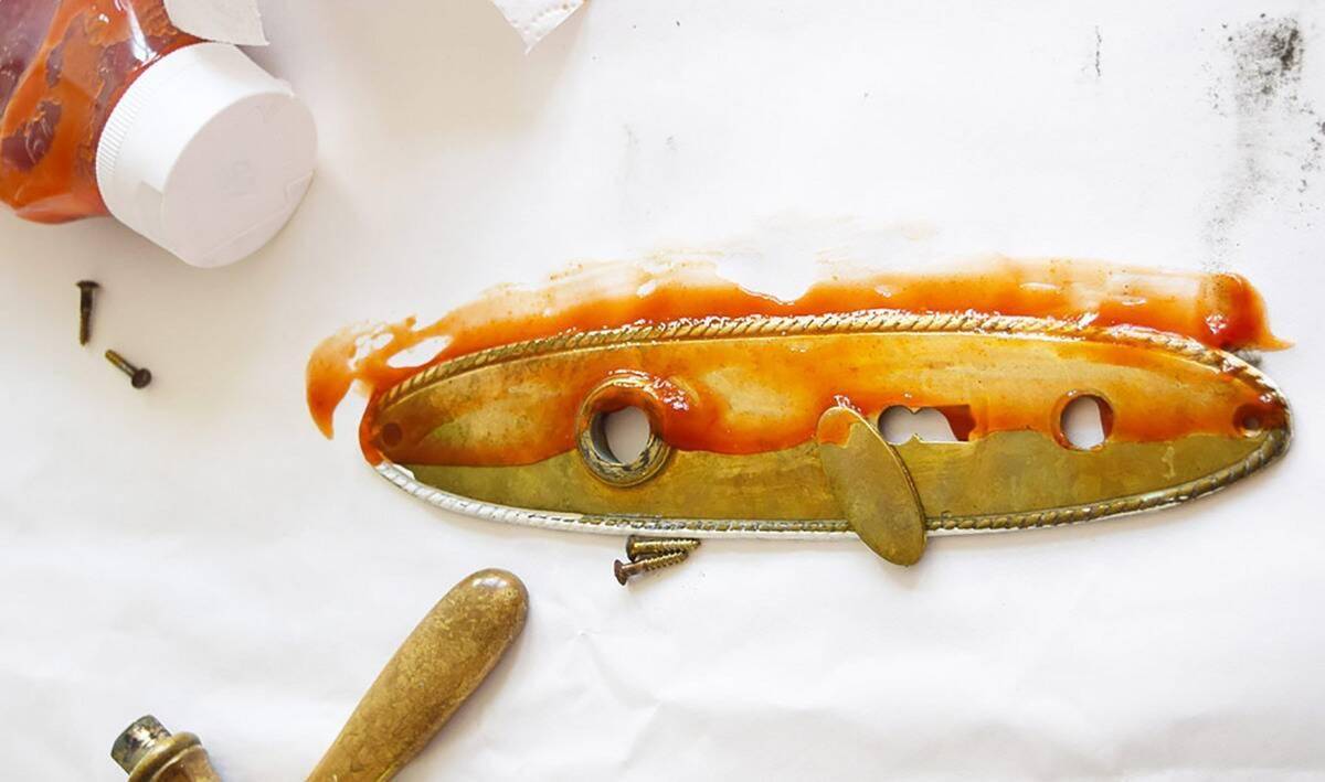 A brass door handle, the top half covered in ketchup.