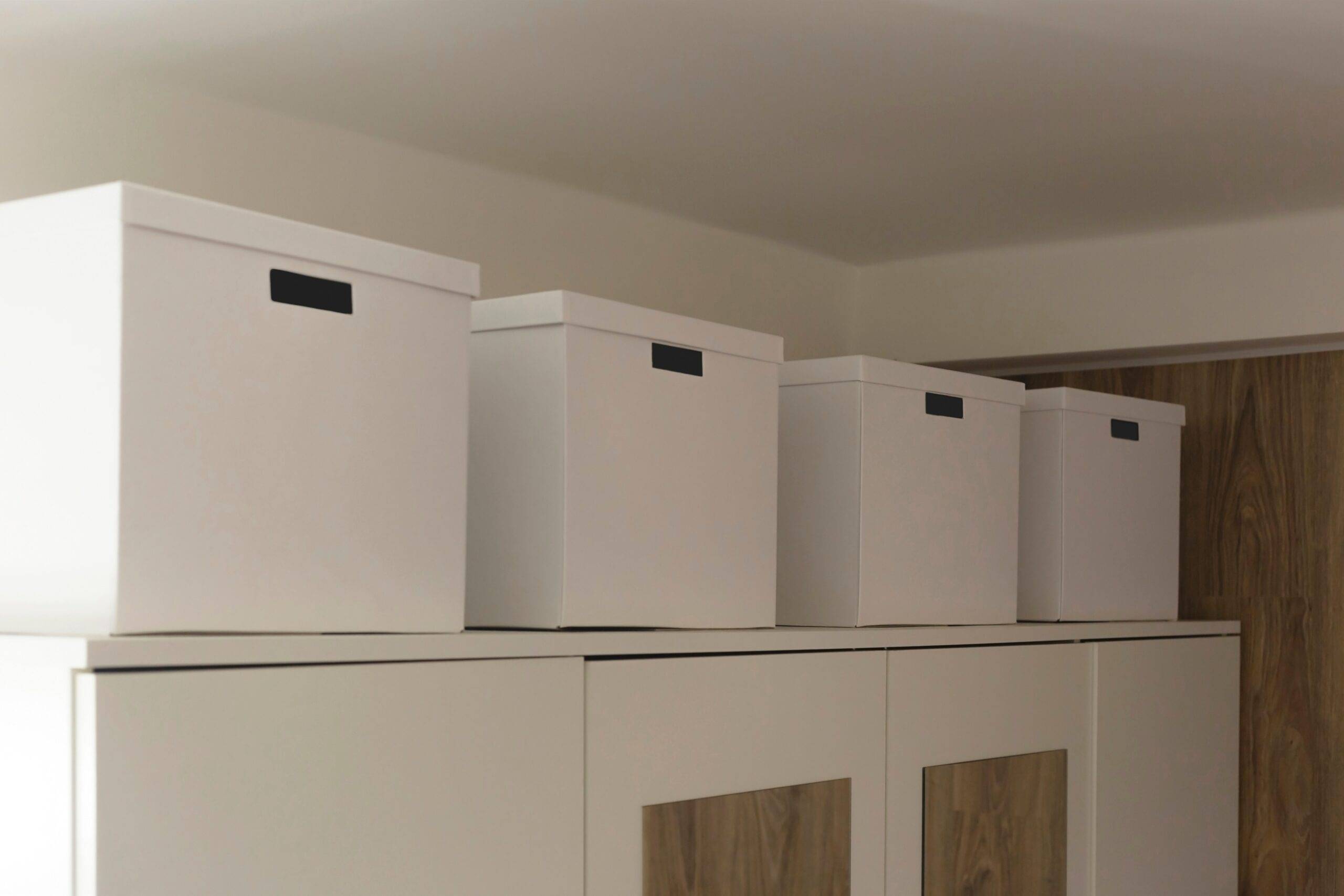 Four large white cardboard boxes on top of a shelf.