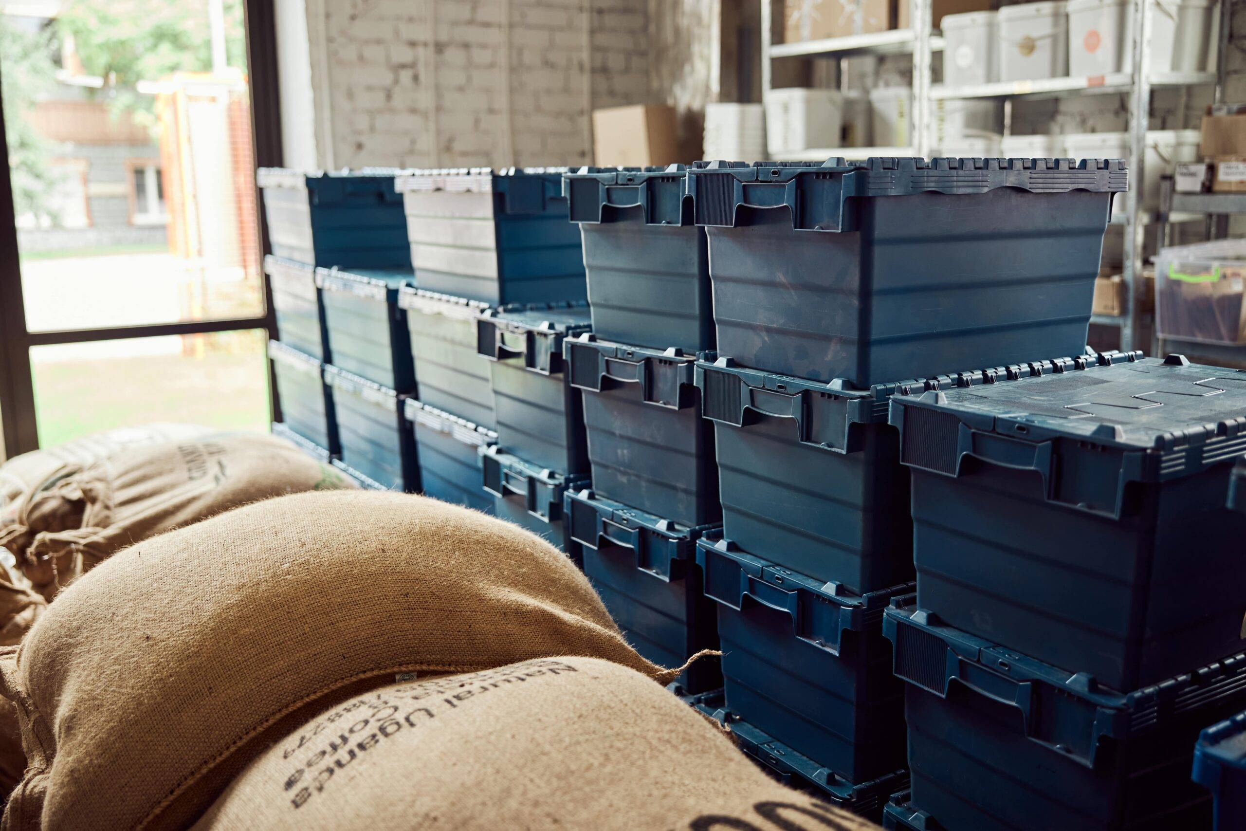 Stacks of plastic storage bins besides burlap sacks.