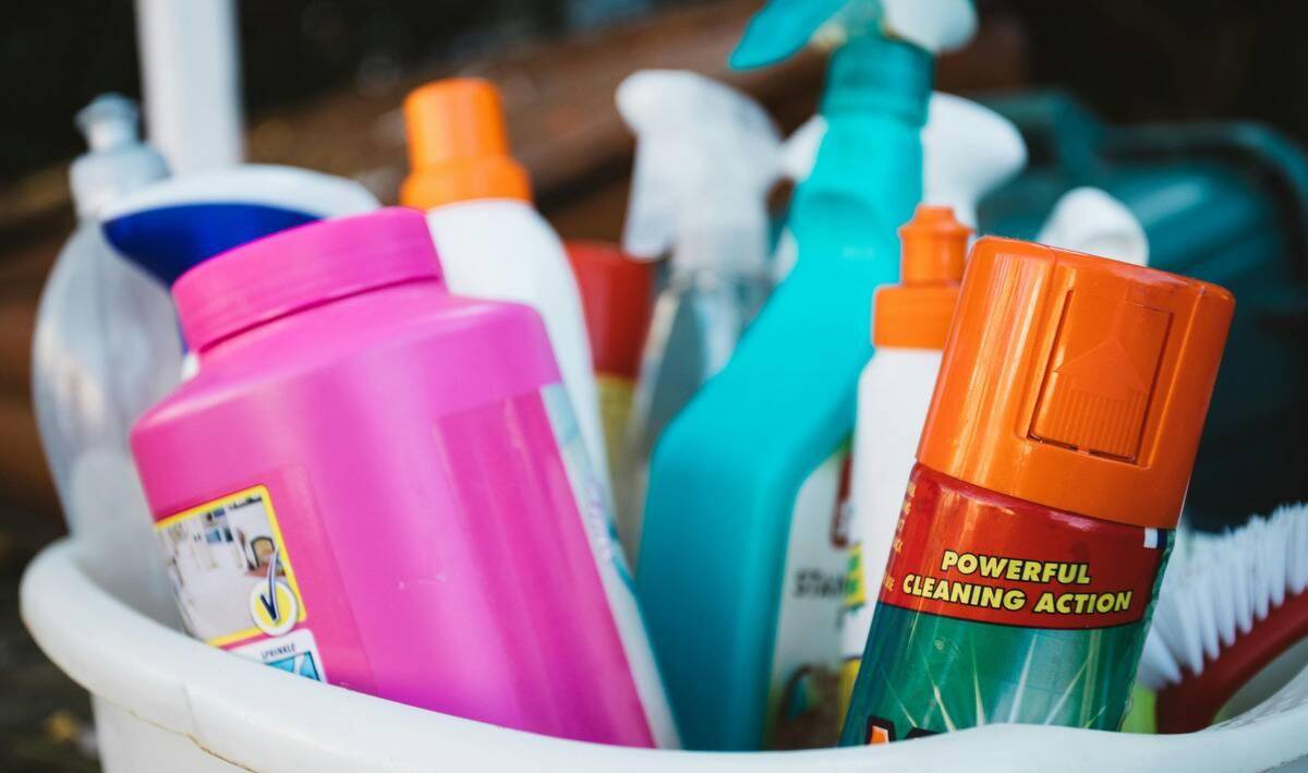 A close photo of a bucket of various cleaning supplies.
