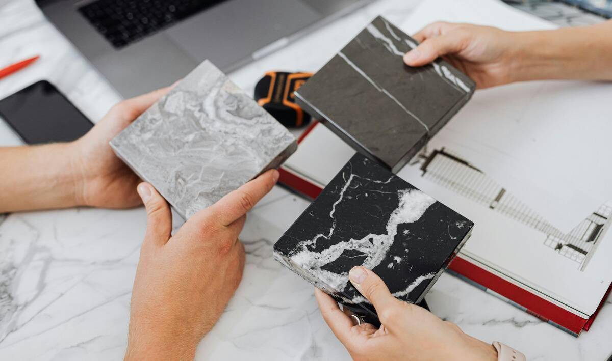 Three hands each holding a tile sample to compare.