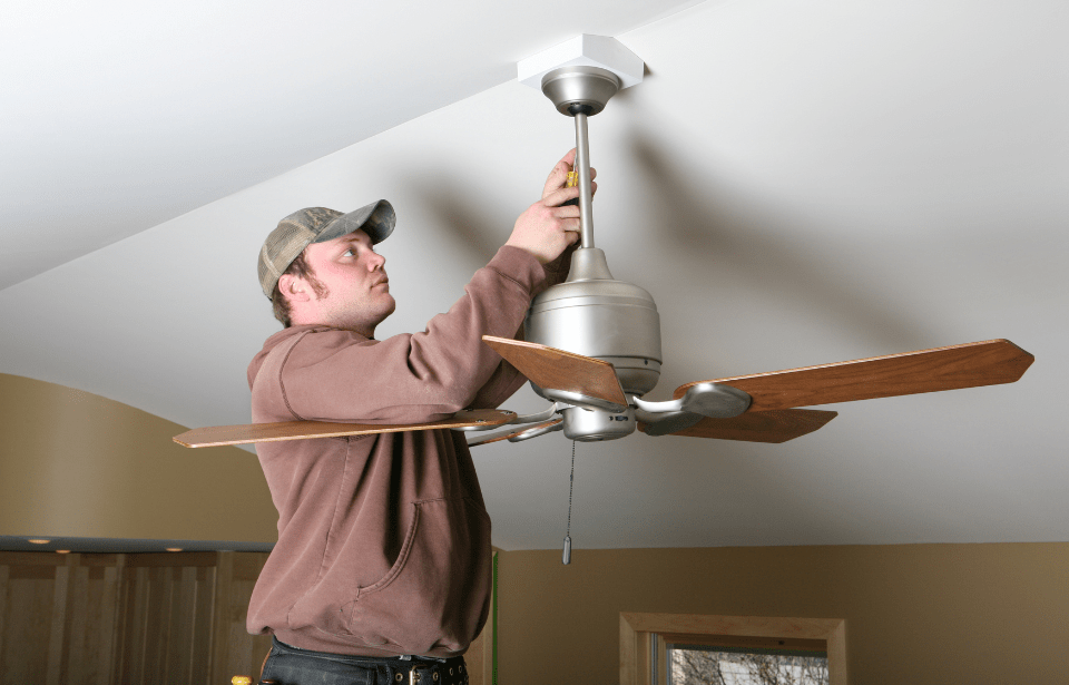 Man adjusting a ceiling fan.