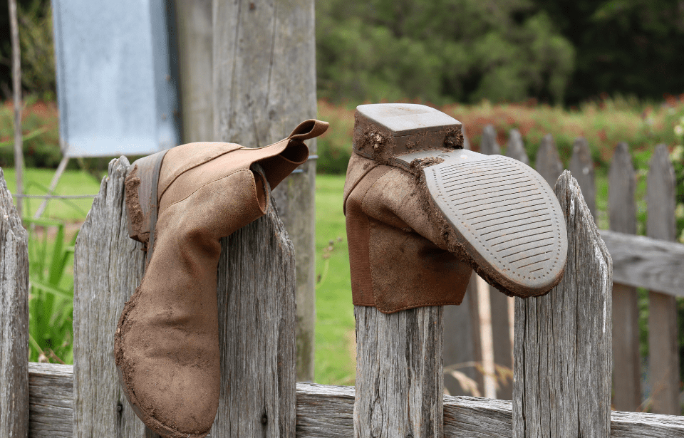 Old boots hung on a picket fence.