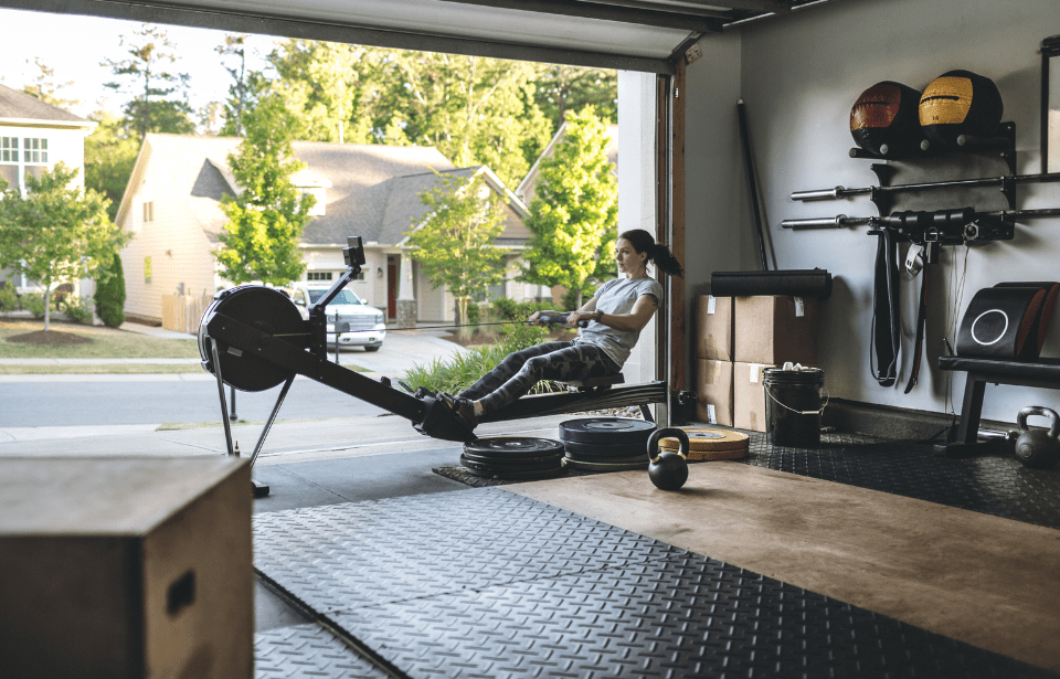 Woman using rowing machine in garage.