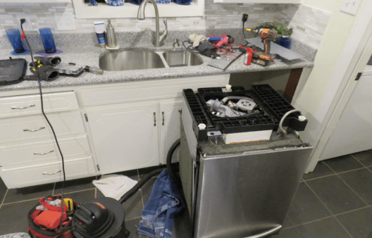 Kitchen dishwasher being repaired.