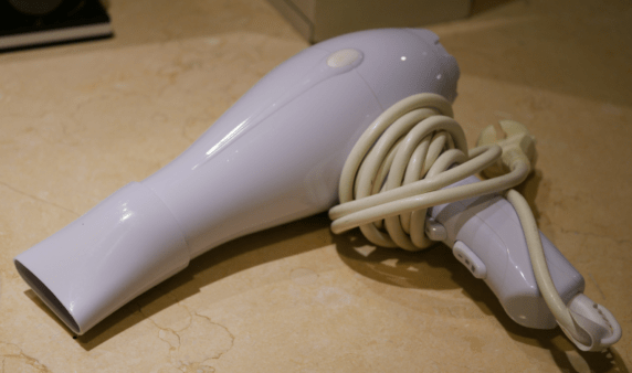 A pale purple hair dryer with the cable wrapped around the handle.