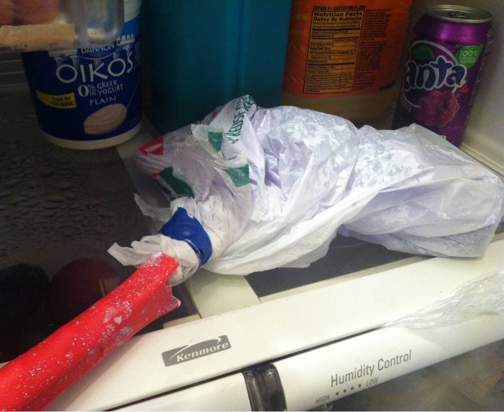 The head of a paint roller, wrapped in a plastic bag and placed into a fridge.