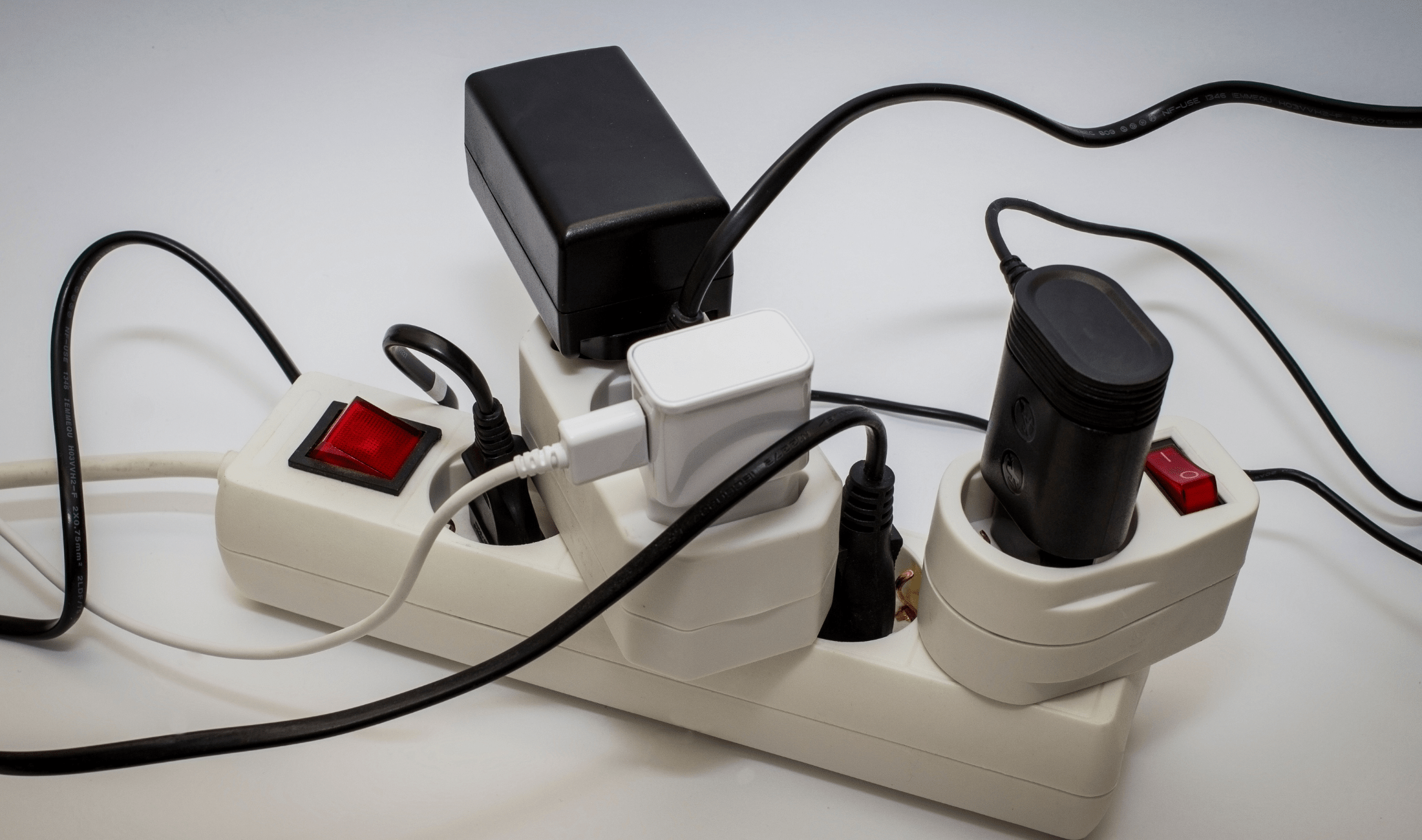 A power strip that's full of plugged in items, including power blocks with even more outlets.