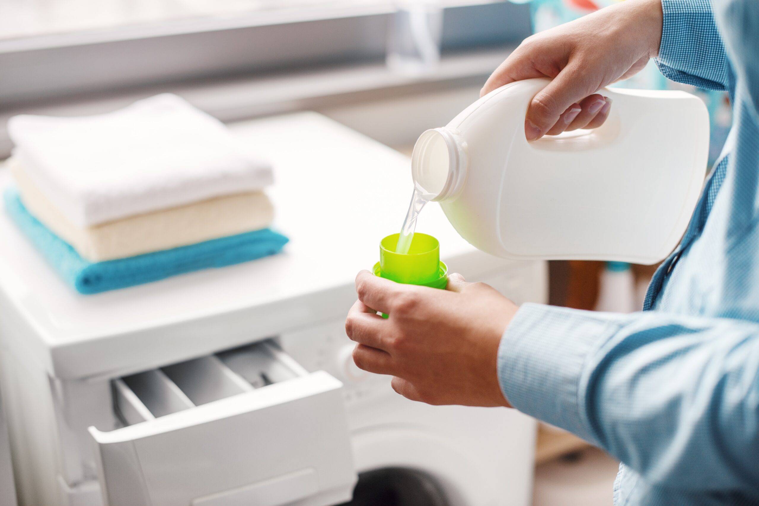 Hands pouring laundry detergent.