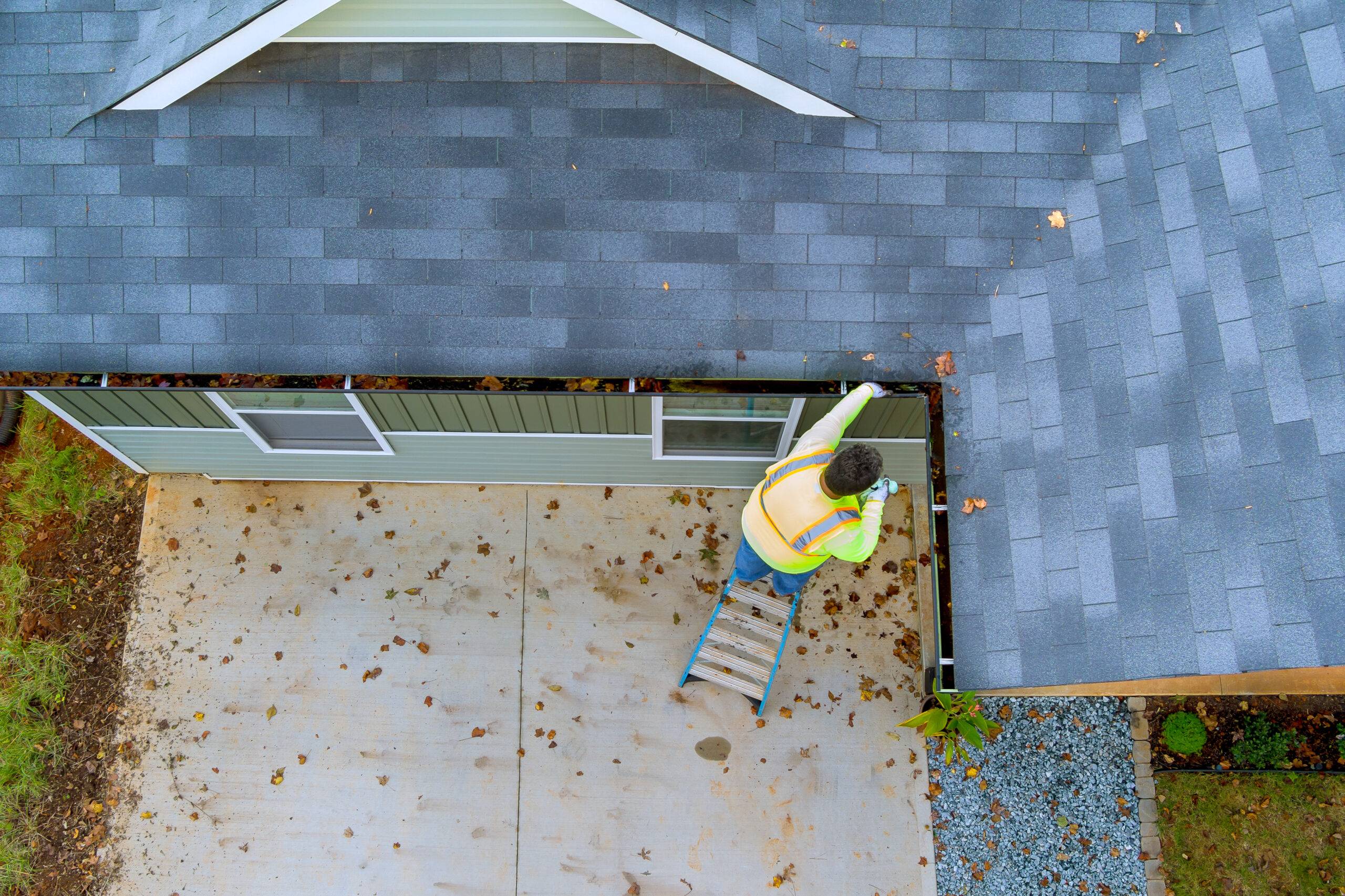 Man on a ladder, cleaning gutters.