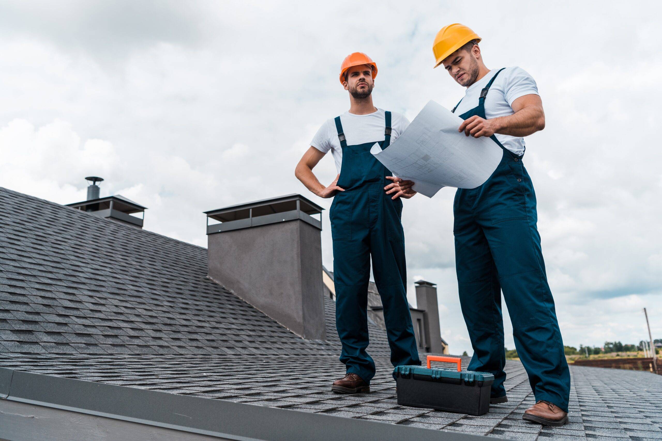 Two builders standing on a roof.