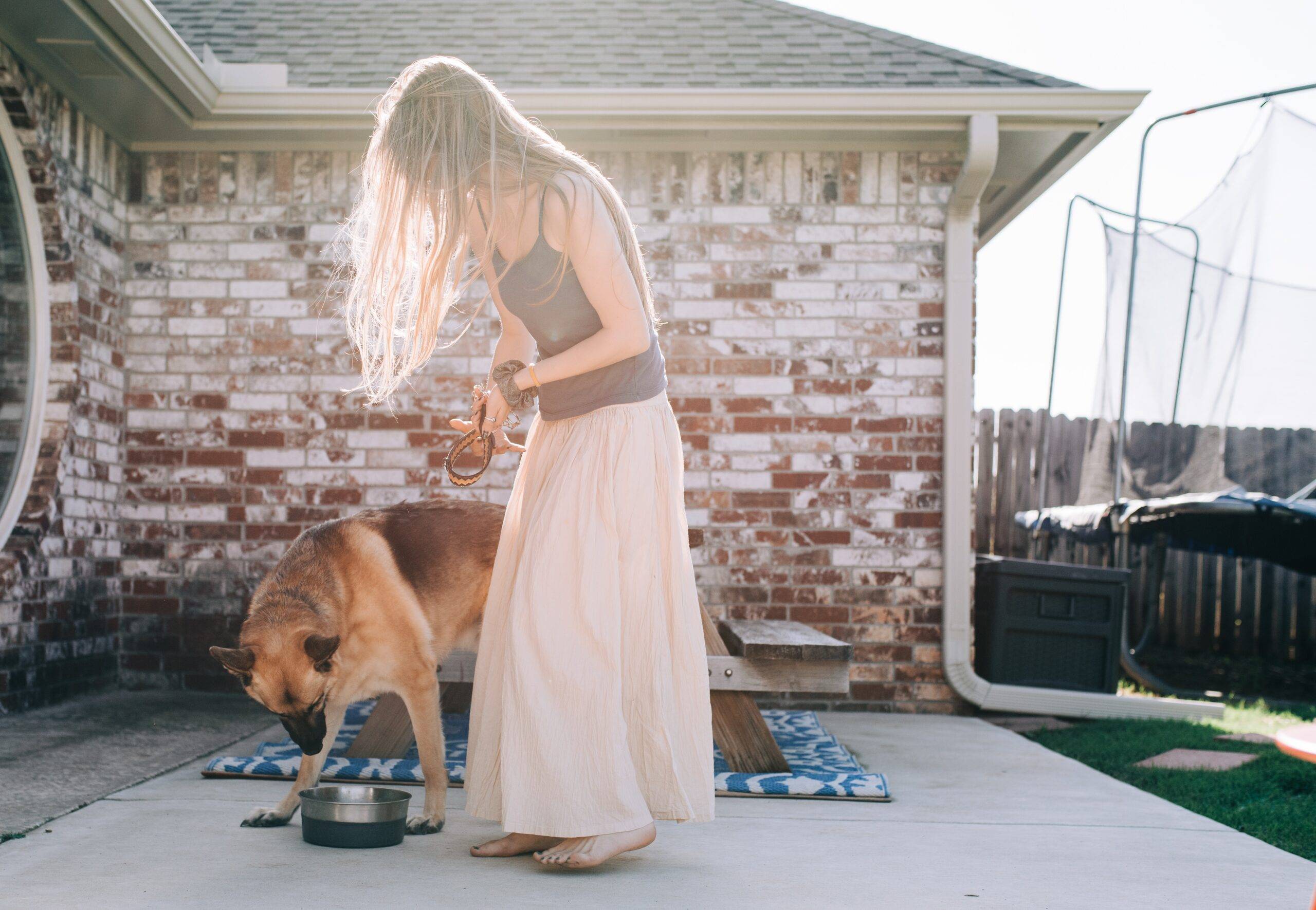 Woman feeding her dog outside.