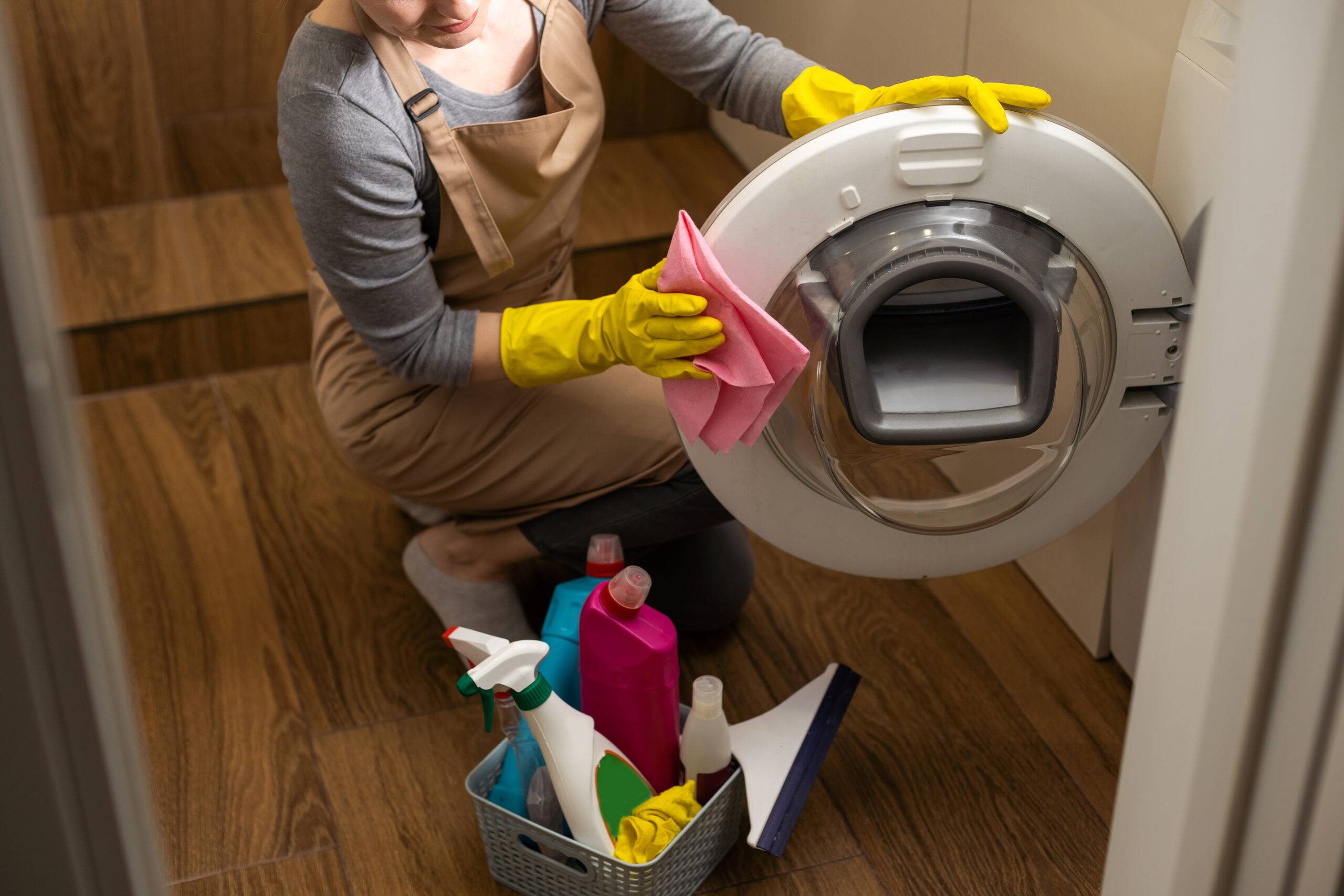 Woman cleaning the inside of a washing machine.