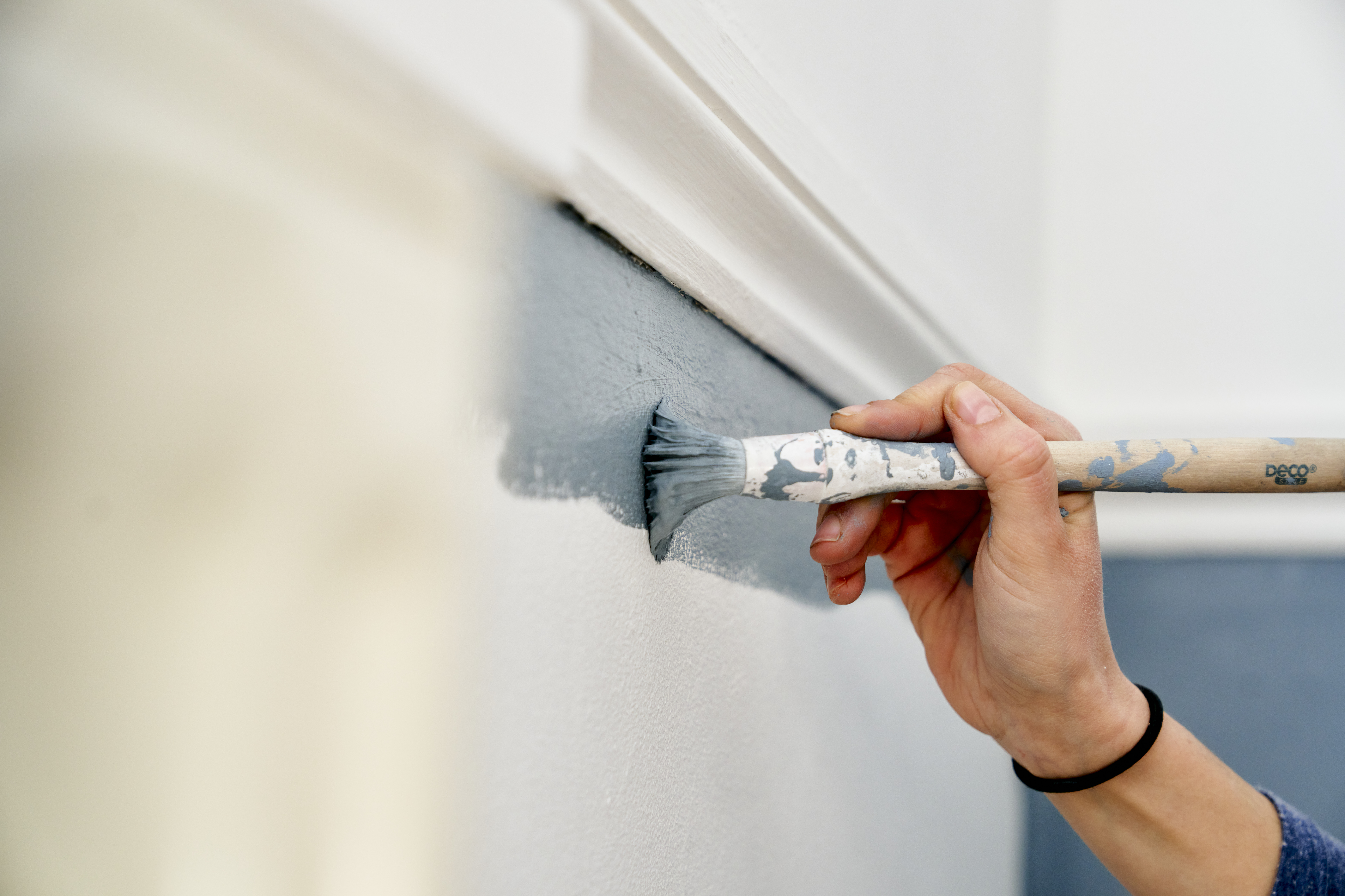 Close up of hand using paintbrush to paint wall