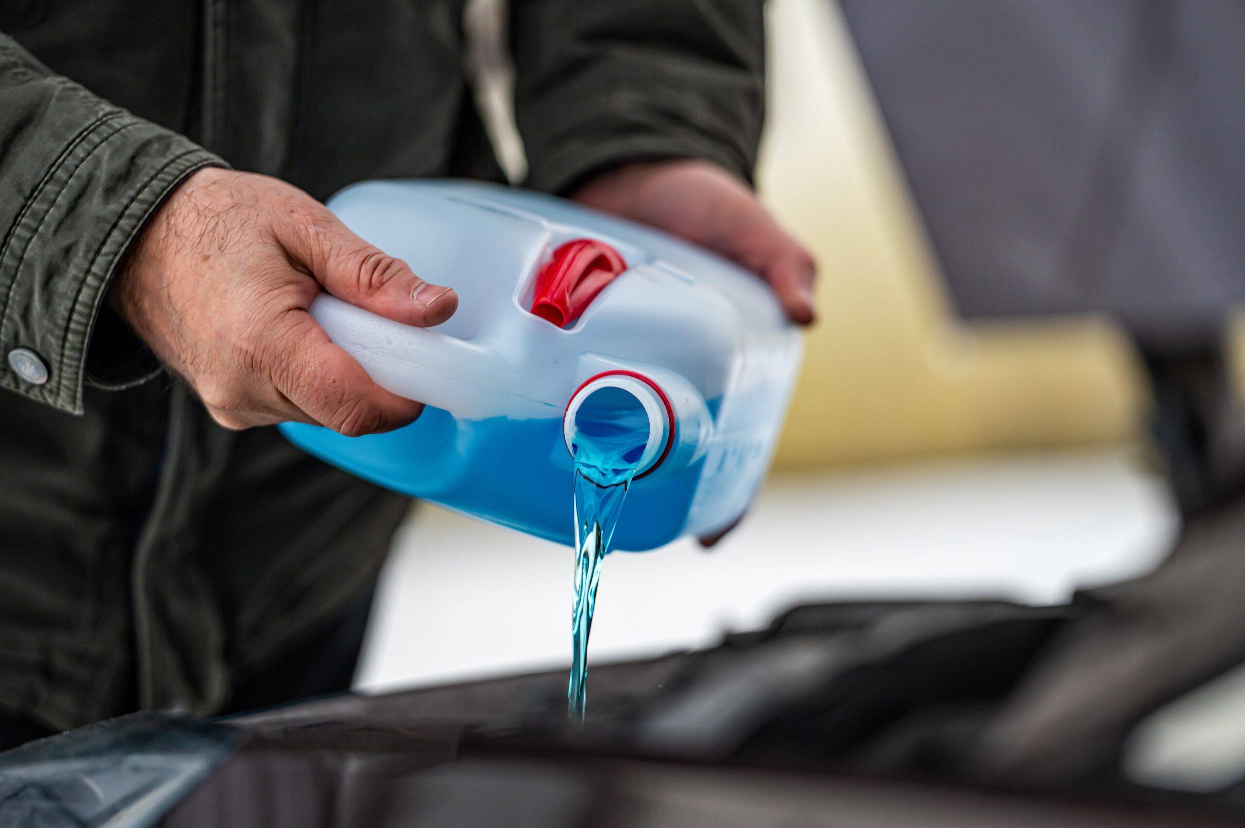Man pouring antifreeze into his car.