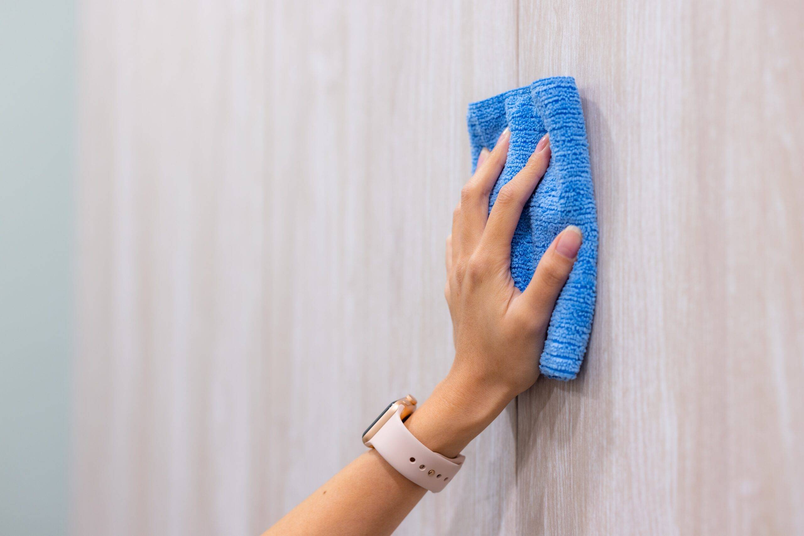 A hand with a cloth wiping a wall down.