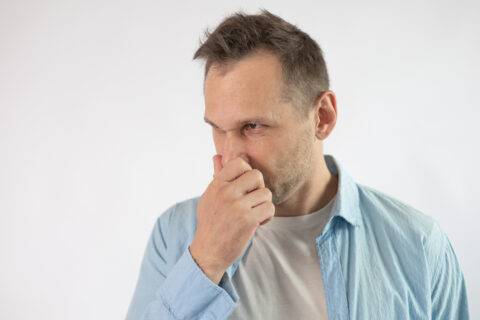Man holding his nose and looking confused.