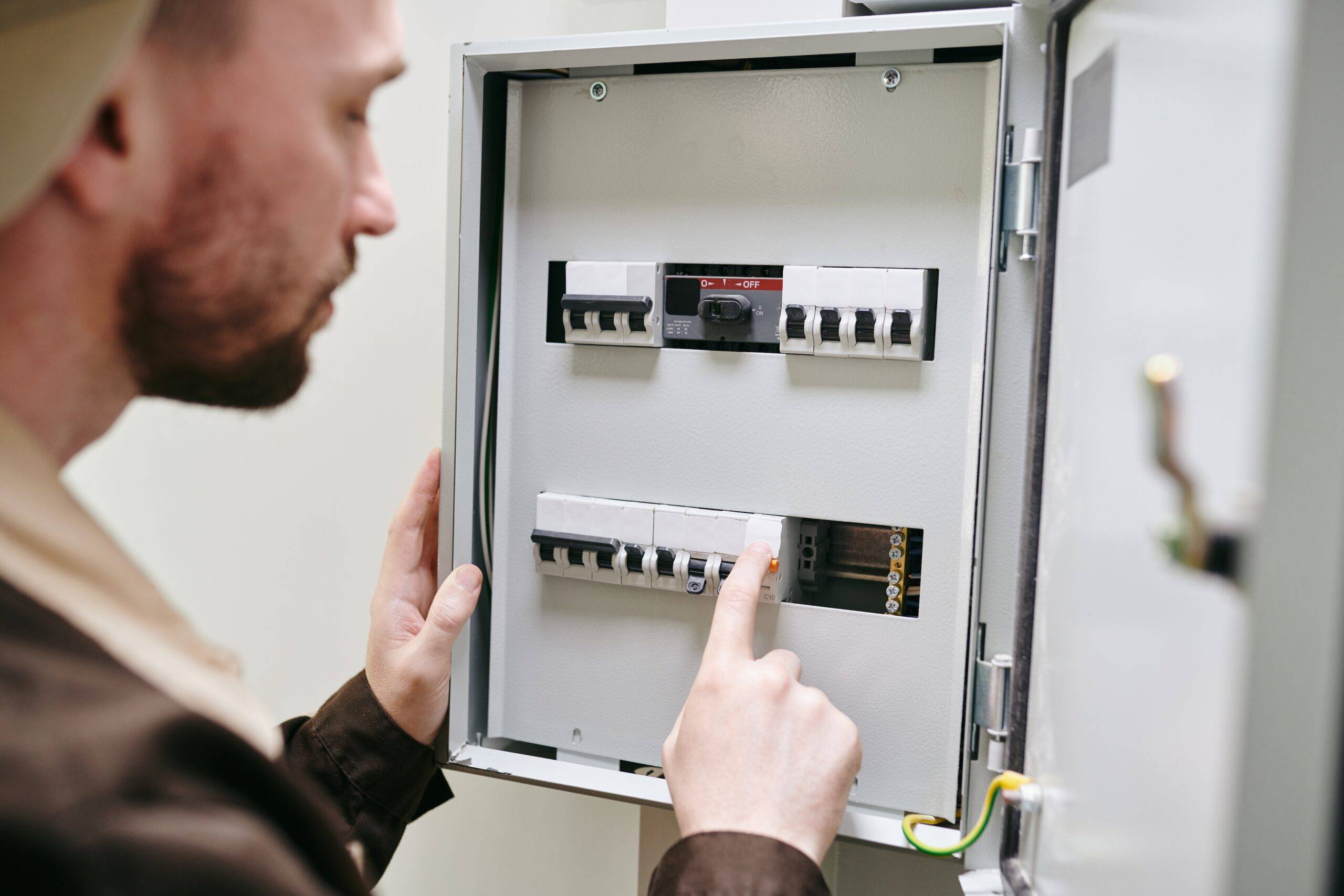 Young man flipping switch on circuit breaker.