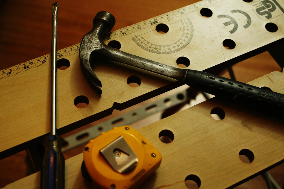 A hammer, screwdriver, measuring tape and a scale kept on a table. 