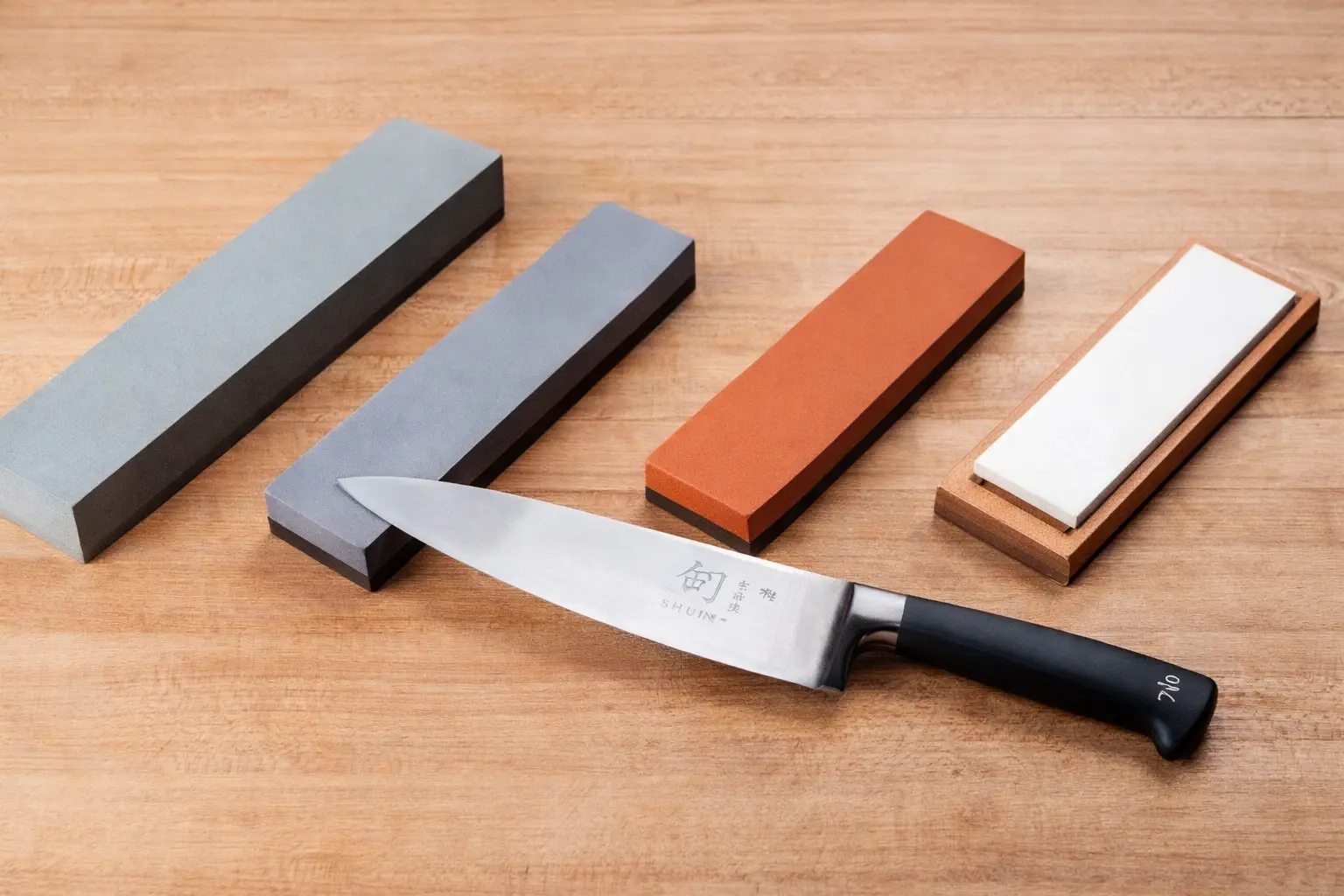 A knife kept next to different levels of whetstones.