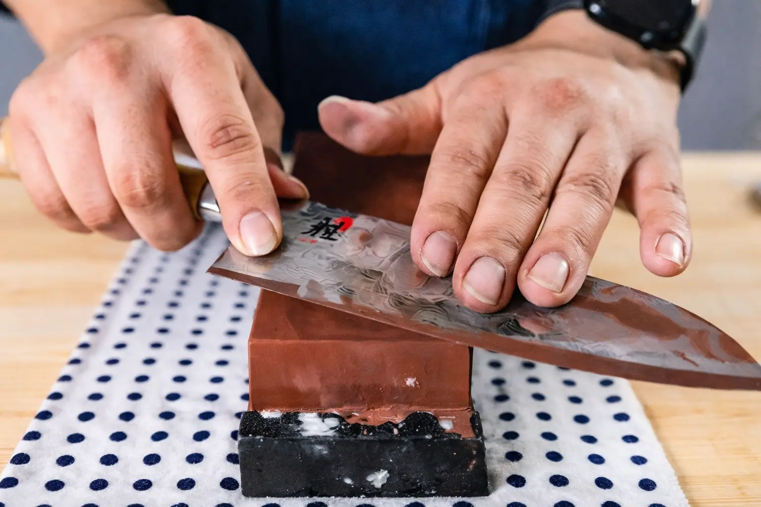 A person sharpening their knife using a whetstone.