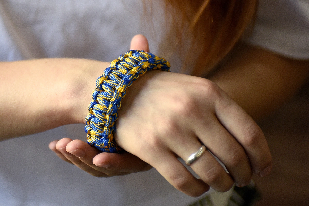 A woman wears a bracelet made out of a piece of paracord.