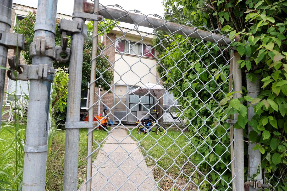 A suburban home as seen through a metal fence.