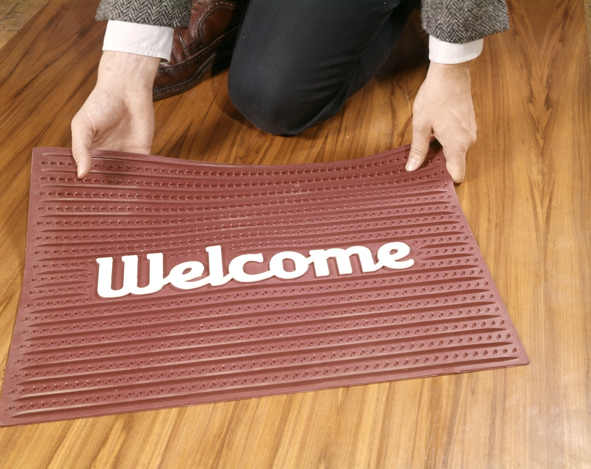 A man picking up a doormat.