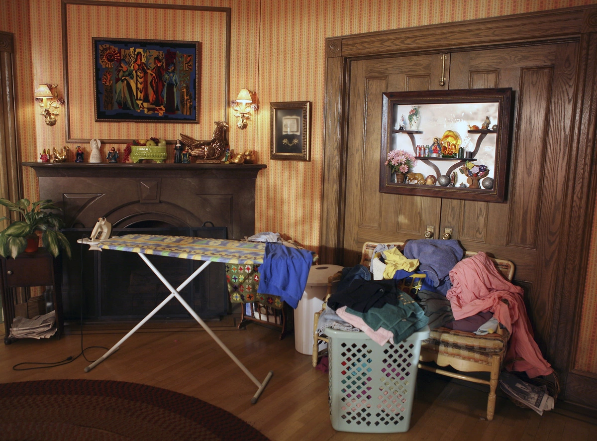 A messy room with clothes strewn about and an overflowing laundry basket.